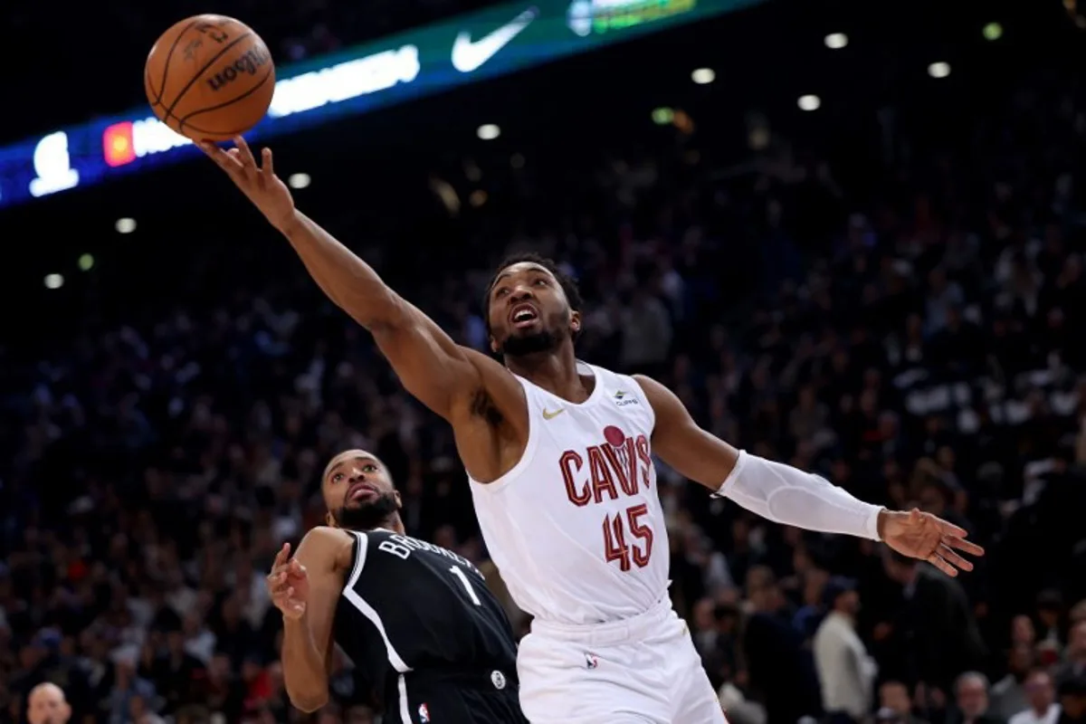 Cleveland Cavaliers' US Point Guard Donovan Mitchell (R) jumps to score in front of Brooklyn Nets' US Point Guard Mikal Bridges (L) during the NBA regular season basketball match between the Cleveland Cavaliers and the Brooklyn Nets at the Accor Arena in Paris on January 11, 2024.  Emmanuel Dunand / AFP