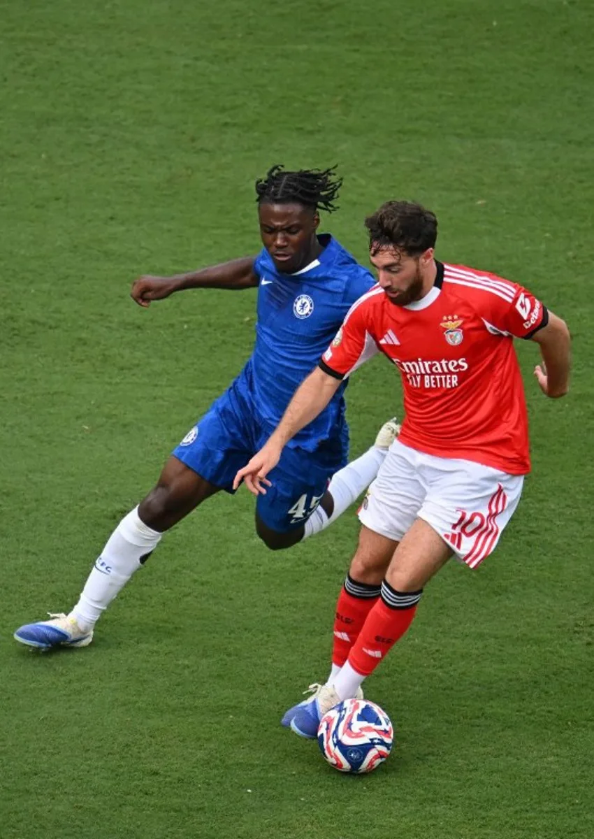 Chelsea's Belgian midfielder #45 Romeo Lavia and Benfica's Turkish midfielder #10 Orkun Kokcu fight for the ball during the FIFA Club World Cup 2025 round of 16 football match between Portugal's Benfica and England's Chelsea at the Bank of America Stadium in Charlotte on June 28, 2025. ANGELA WEISS / AFP