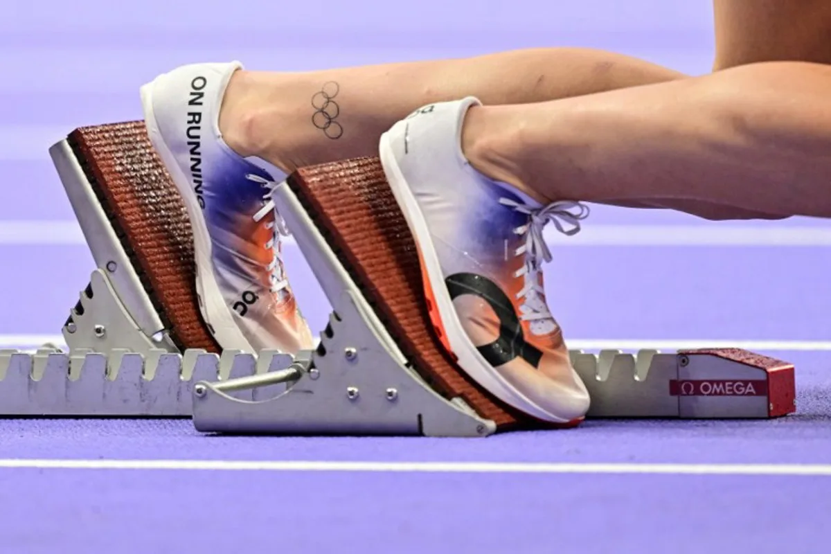 An athlete with Olympic rings' tattoo on her leg prepares to compete in the women's 4x100m relay final of the athletics event at the Paris 2024 Olympic Games at Stade de France in Saint-Denis, north of Paris, on August 9, 2024.  Martin  BERNETTI / AFP