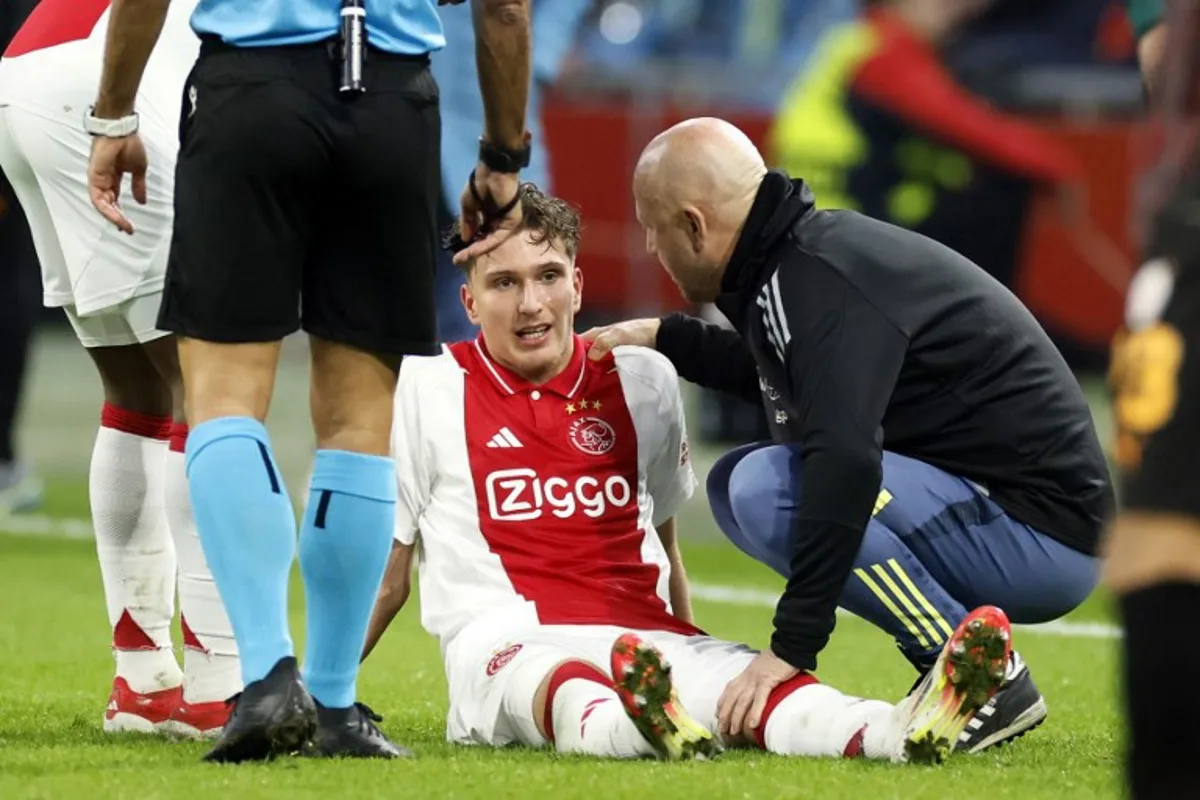 Ajax's Belgian forward #11 Mika Godts (C) receives medical attention during the UEFA Europa League, 1st round day 8, football match between Ajax Amsterdam and Galatasaray at Johan Cruijff ArenA stadium in Amsterdam on January 30, 2025.  Koen van Weel / ANP / AFP