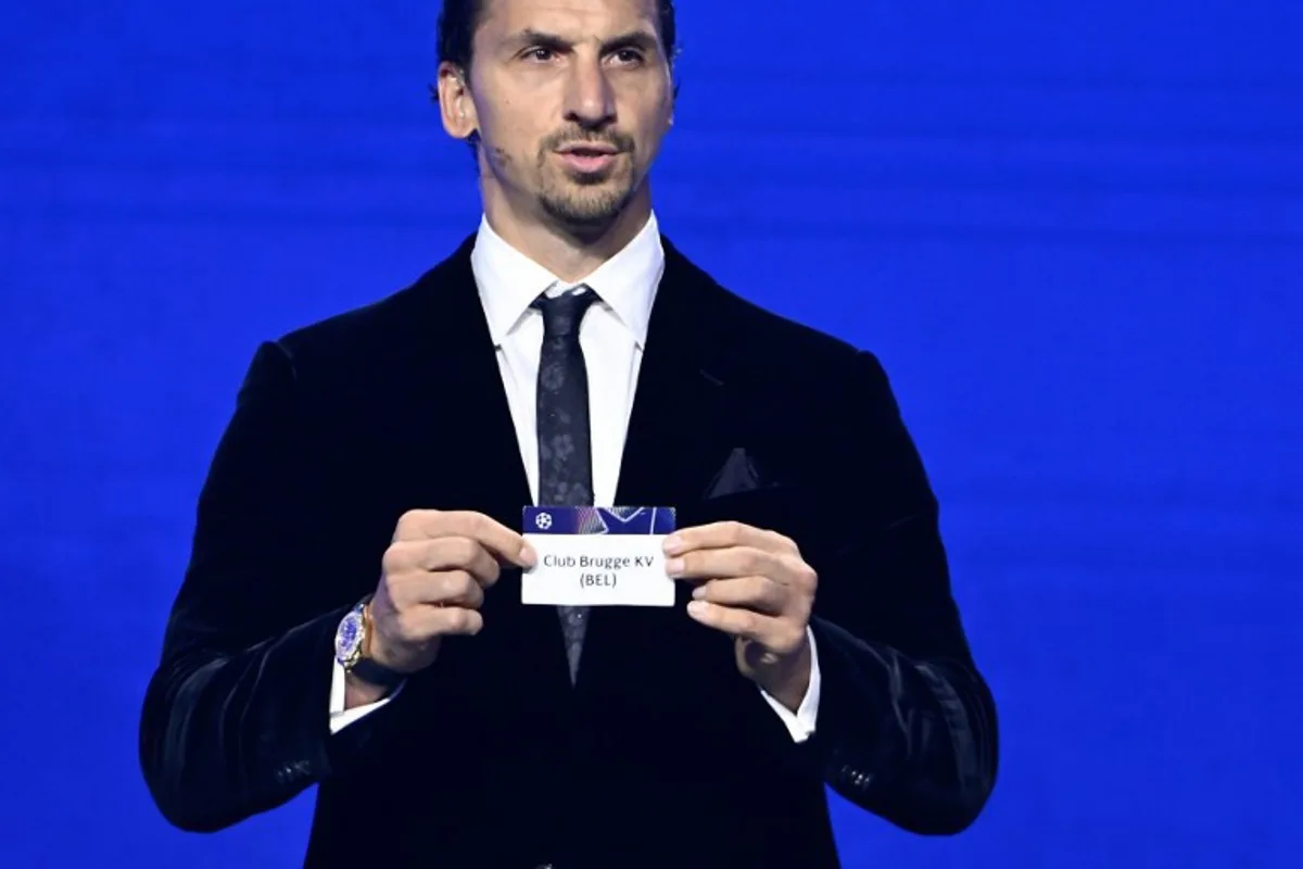 AC Milan's Swedish senior advisor Zlatan Ibrahimovic holds up the slip of Club Brugge during the draw ceremony for the group stage of the 2025-2026 UEFA Champions League football tournament, at the Grimaldi Forum in Monaco on August 28, 2025. Frederic DIDES / AFP