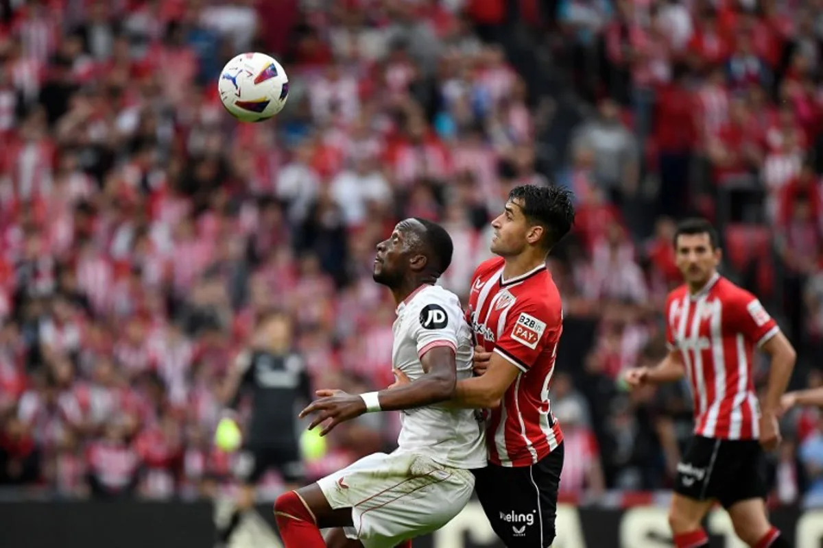 Sevilla's Belgian forward #11 Dodi Lukebakio (L) fights for the ball with Athletic Bilbao's Spanish midfielder #24 Benat Prados during the Spanish League football match between Athletic Club Bilbao and Sevilla FC at the San Mames stadium in Bilbao on May 19, 2024.  ANDER GILLENEA / AFP