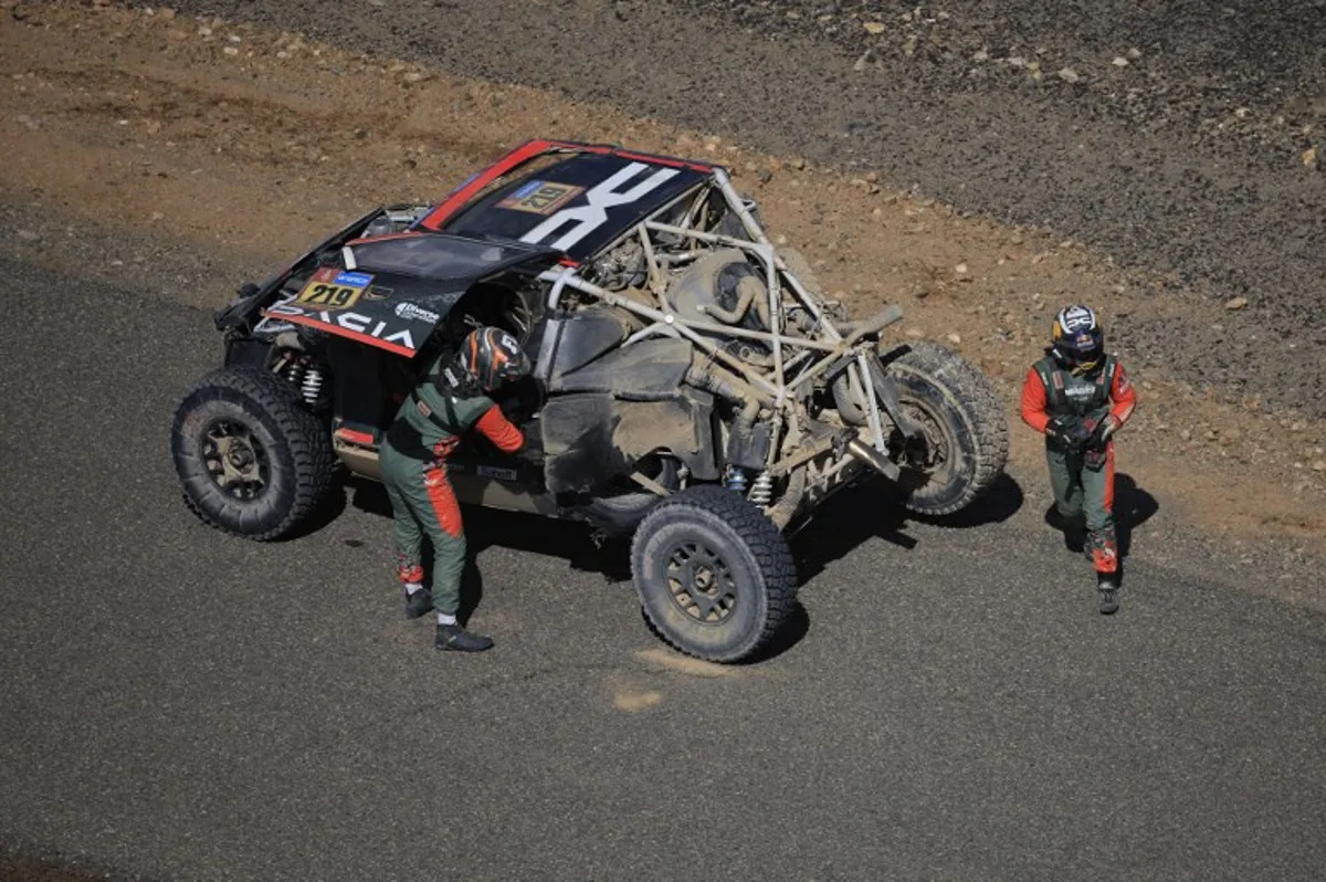 The Dacia of French driver Sebastien Loeb and co-driver Fabian Lurguin is stopped on the road after crashing during stage 3 of the 47th Dakar Rally, between Bisha and Al Henakiyah, on January 7, 2025.  Valery HACHE / AFP