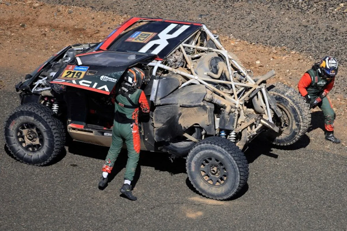 French driver Sebastien Loeb and Belgian co-driver Fabian Lurquin stands near their Dacia Sandrider vehicle after crashing during stage 3 of the 47th Dakar Rally between Bisha and al-Henakiyah, on January 7, 2025.  Valery HACHE / AFP