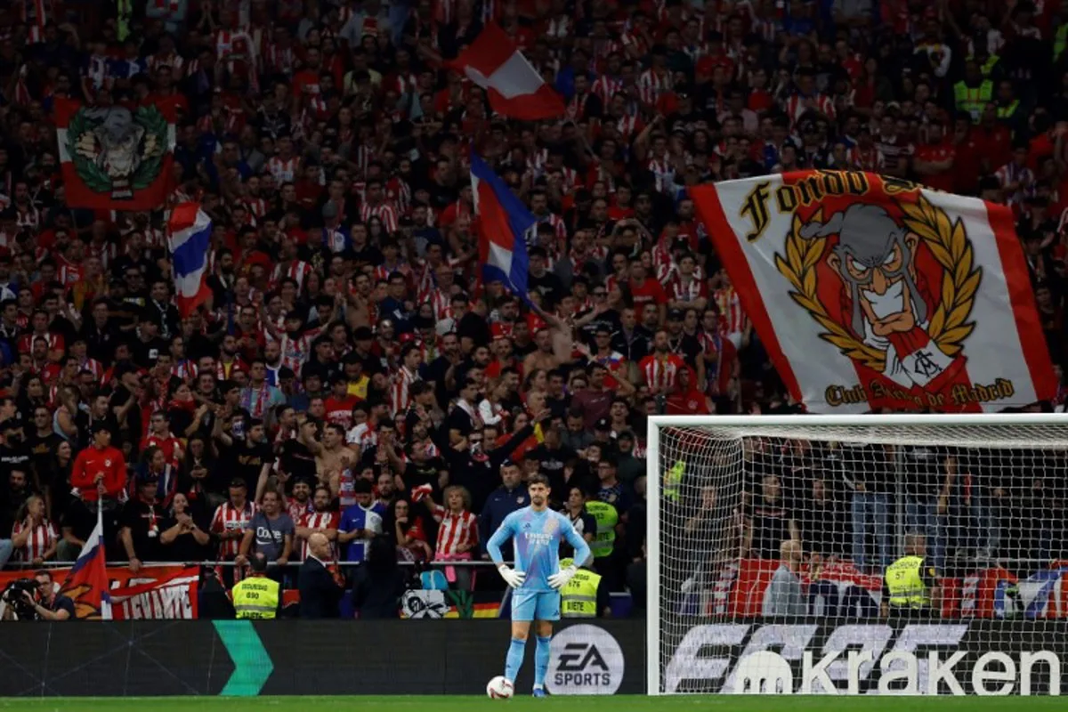 Real Madrid's Belgian goalkeeper #01 Thibaut Courtois waits after Atletico Madrid's supporters sent items on the pitch following Brazilian defender #03 Eder Militao's goal during the Spanish league football match between Club Atletico de Madrid and Real Madrid CF at the Metropolitano stadium in Madrid on September 29, 2024.  OSCAR DEL POZO / AFP