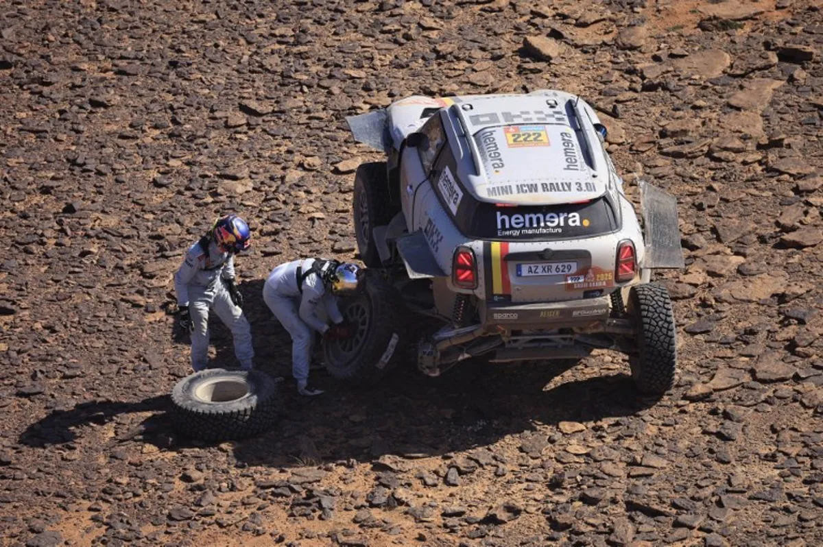 Belgian pilots Guillaume De Mevius and co-driver Mathieu Baumel change a wheel as they compete during stage 4 of the 47th Dakar Rally 2025 between Al Henakiyak and Alula, on January 8, 2025.  Valery HACHE / AFP