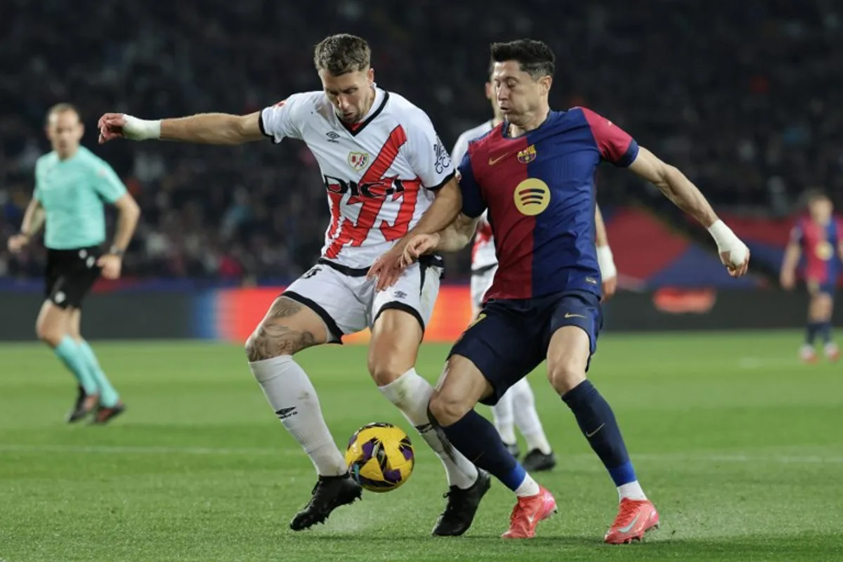 Barcelona's Polish forward #09 Robert Lewandowski (R) is challenged by Rayo Vallecano's French defender #24 Florian Lejeune during the Spanish league football match between FC Barcelona and Rayo Vallecano de Madrid at the Estadi Olimpic Lluis Companys in Barcelona on February 17, 2025.  LLUIS GENE / AFP