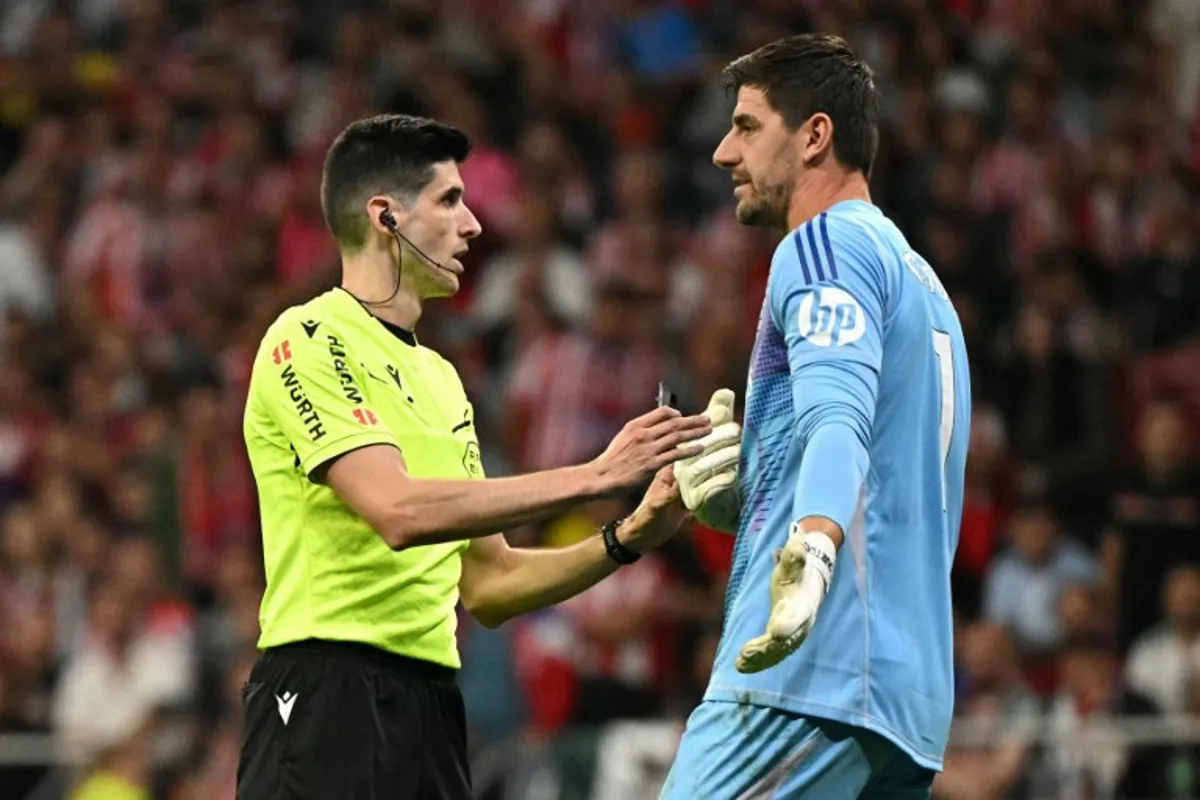 Spanish referee Mateo Busquets talks with Real Madrid's Belgian goalkeeper #01 Thibaut Courtois during the Spanish league football match between Club Atletico de Madrid and Real Madrid CF at the Metropolitano stadium in Madrid on September 29, 2024.  JAVIER SORIANO / AFP