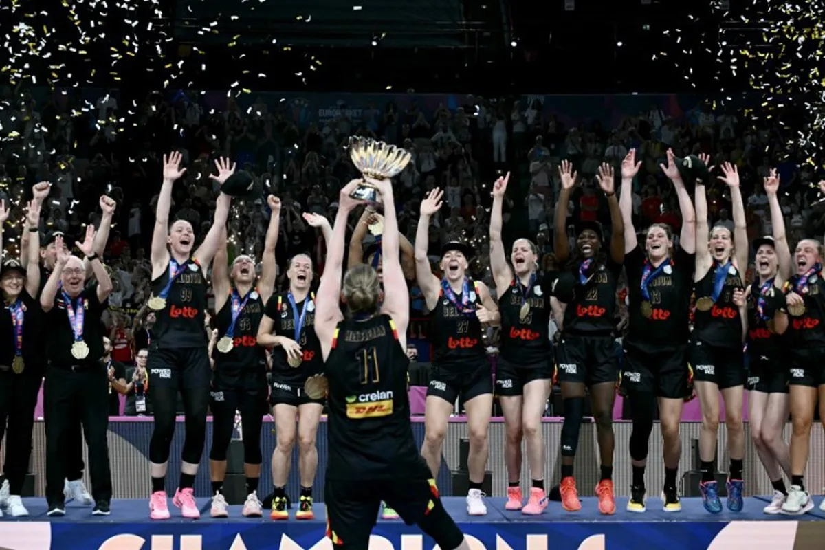 Belgium's power forward Emma Meesseman (C) holds the trophy and celebrates with teammates winning the 2025 FIBA Women's EuroBasket after their final match against Spain at the Peace and Friendship Stadium in Athens on June 29, 2025. Aris MESSINIS / AFP