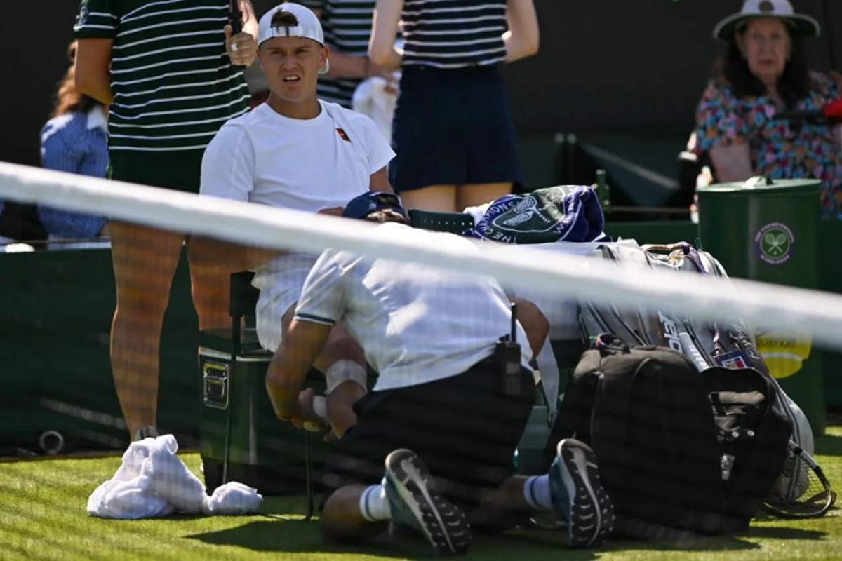Denmark's Holger Rune receives medical treatment as he plays against Chile's Nicolas Jarry during their men's singles first round tennis match on the first day of the 2025 Wimbledon Championships at The All England Lawn Tennis and Croquet Club in Wimbledon, southwest London, on June 30, 2025. Glyn KIRK / AFP