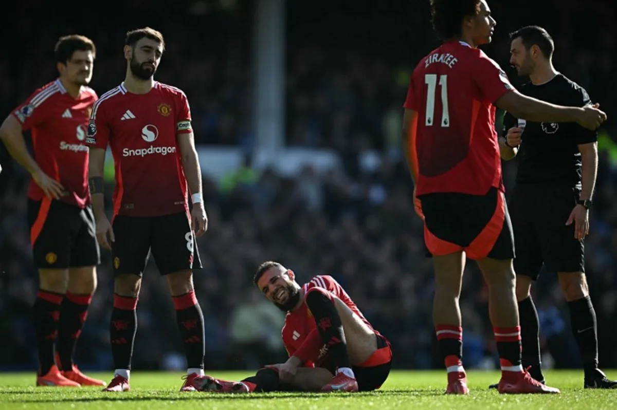 Manchester United's Moroccan defender #03 Noussair Mazraoui holds his leg as he lays injured on the pitch during the English Premier League football match between Everton and Manchester United at Goodison Park in Liverpool, north west England on February 22, 2025.  Paul ELLIS / AFP