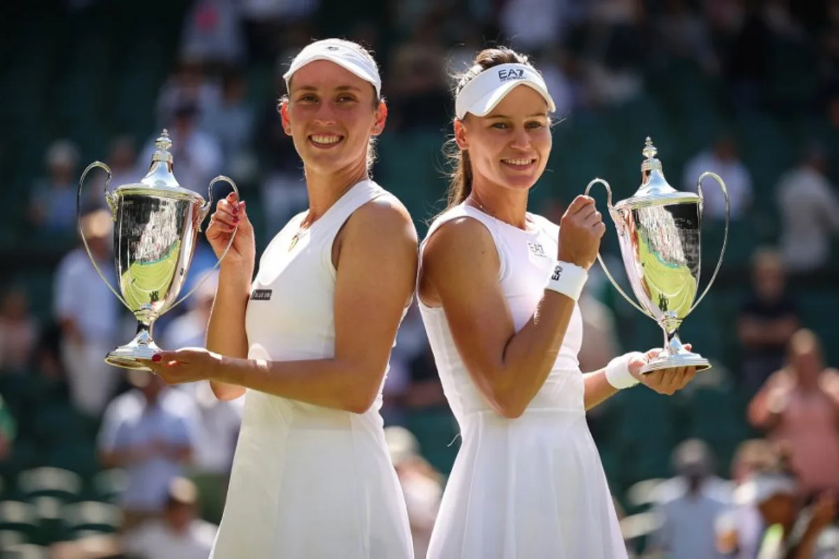 First-placed Russia's Veronika Kudermetova (R) and Belgium's Elise Mertens pose with their trophies after winning against Taiwan's Hsieh Su-wei and Latvia's Jelena Ostapenko at the end of their women's doubles final tennis match on the fourteenth day of the 2025 Wimbledon Championships at The All England Lawn Tennis and Croquet Club in Wimbledon, southwest London, on July 13, 2025. HENRY NICHOLLS / AFP