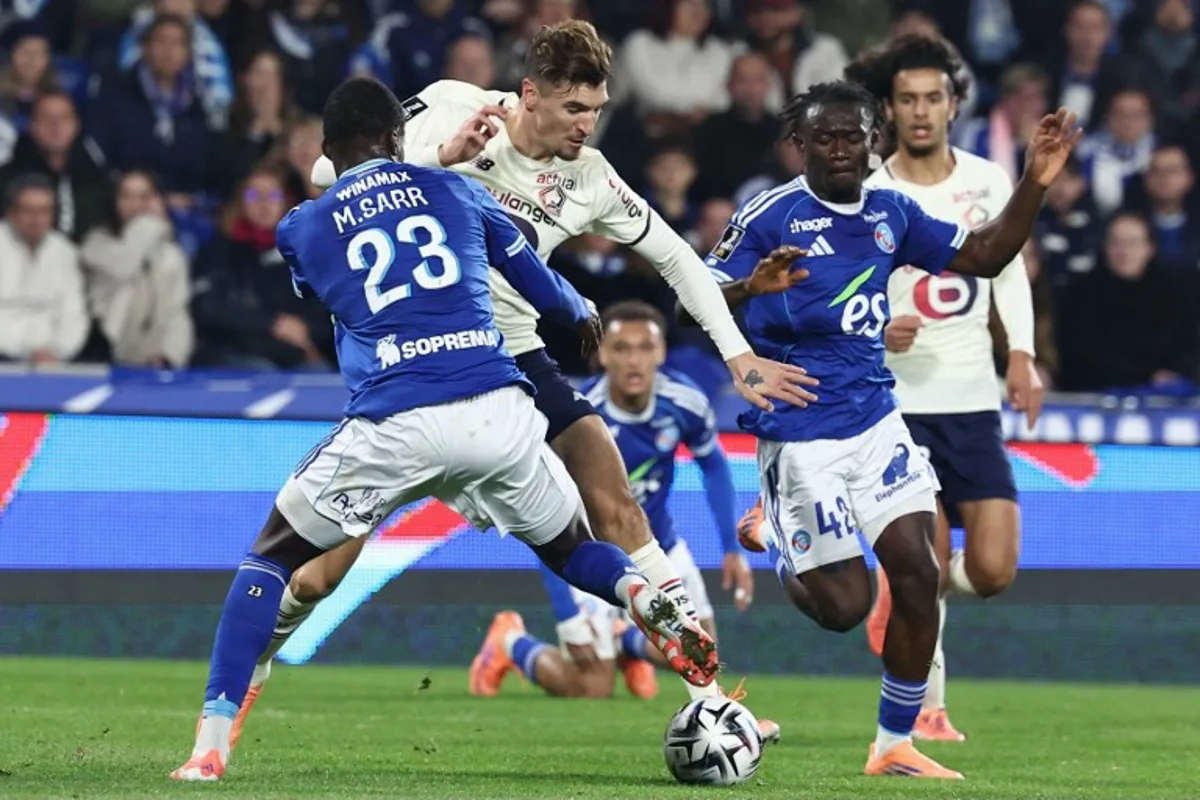 Lille's Belgian defender #12 Thomas Meunier (C) fights for the ball with Strasbourg's French defender #23 Mamadou Sarr during the French L1 football match between RC Strasbourg Alsace and Lille LOSC at the Stade de la Meinau in Strasbourg, eastern France, on November 9, 2025. Frederick FLORIN / AFP