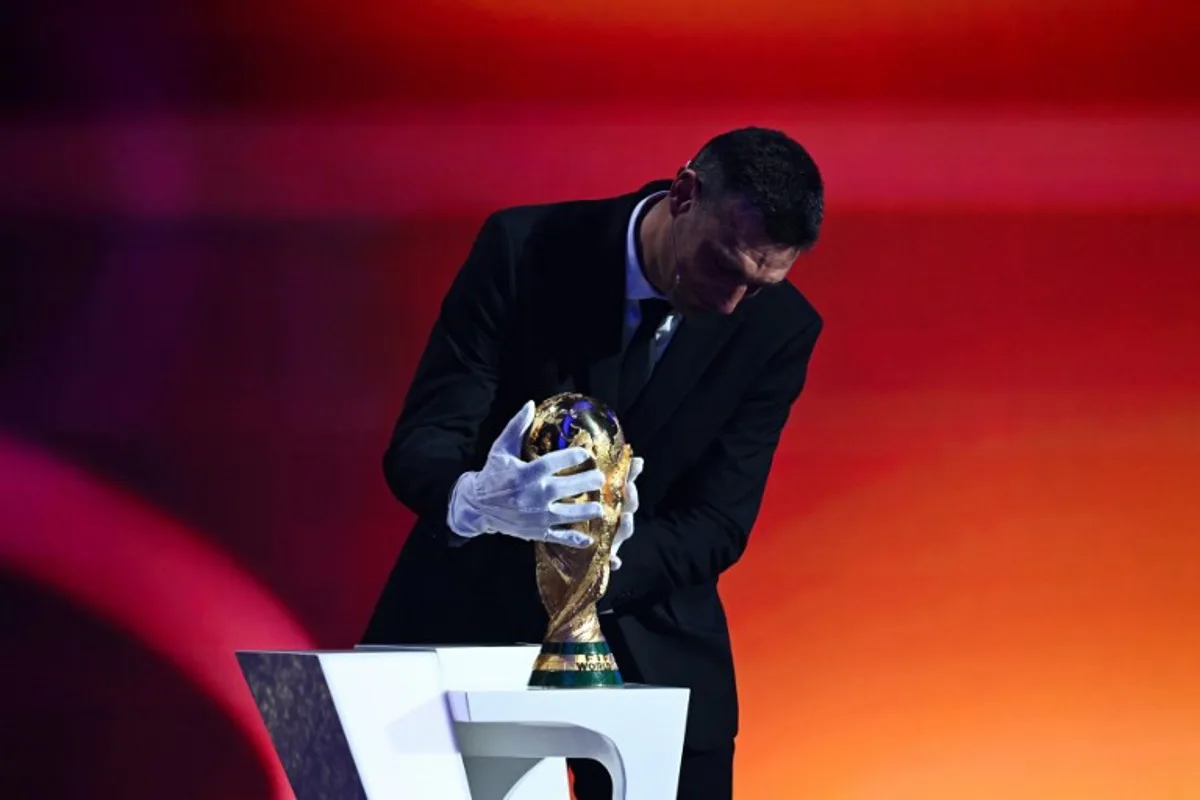 Argentina's head coach Lionel Scaloni places the FIFA World Cup trophy on stage during the draw for the 2026 FIFA Football World Cup taking place in the US, Canada and Mexico, at the Kennedy Center, in Washington, DC, on December 5, 2025. SAUL LOEB / AFP