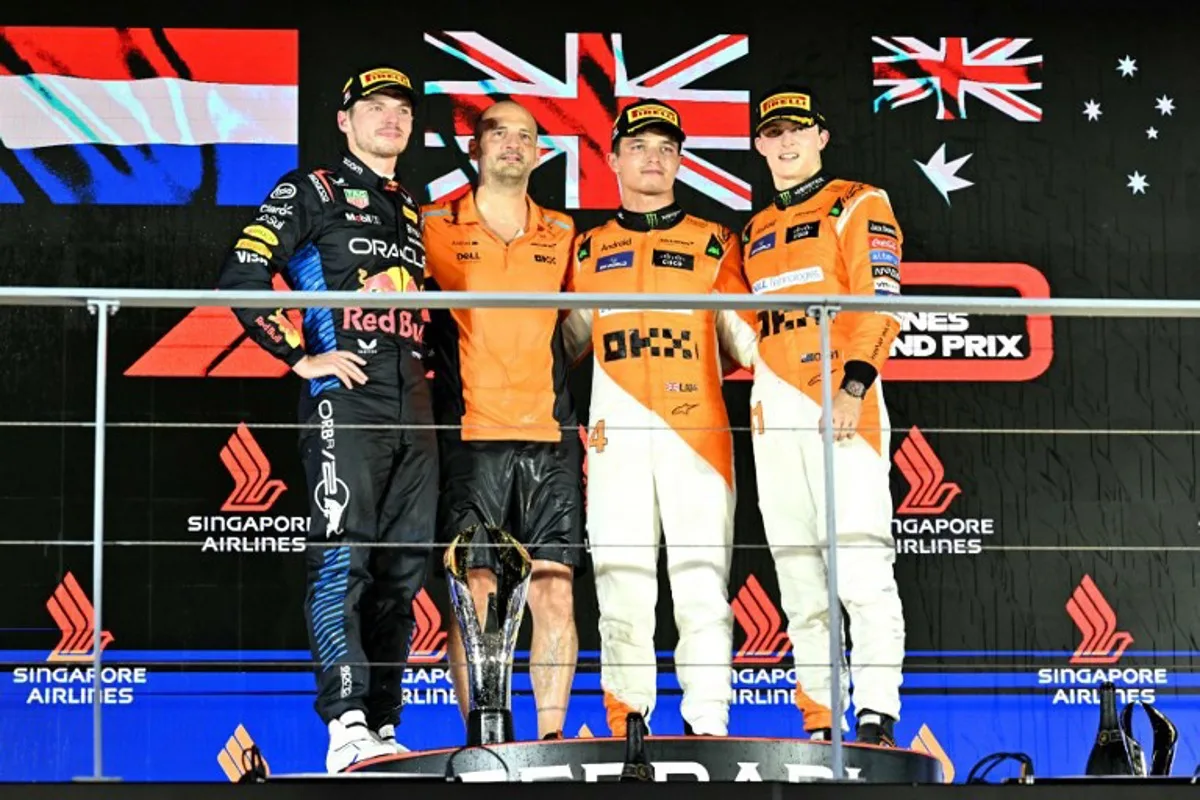 First placed McLaren's British driver Lando Norris (2nd R) celebrates winning next to second placed Red Bull Racing's Dutch driver Max Verstappen (L) and third placed McLaren's Australian driver Oscar Piastri (R) on the podium after the Formula One Singapore Grand Prix night race at the Marina Bay Street Circuit in Singapore on September 22, 2024.  MOHD RASFAN / AFP