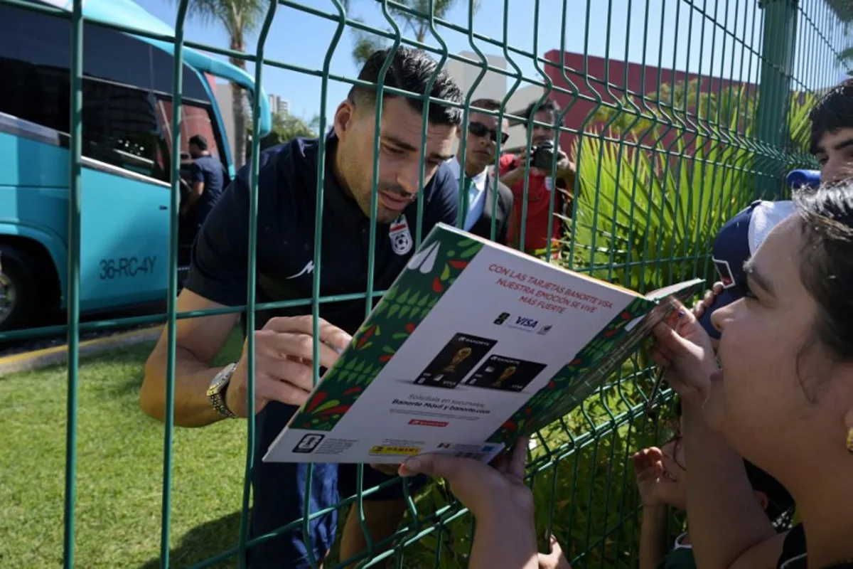 Iran's forward Mehdi Taremi signs autographs for a fan outside the Marriott Hotel before leaving for a training session in Tijuana, Mexico, on June 10, 2026, ahead of the 2026 FIFA World Cup football tournament.  Guillermo Arias / AFP