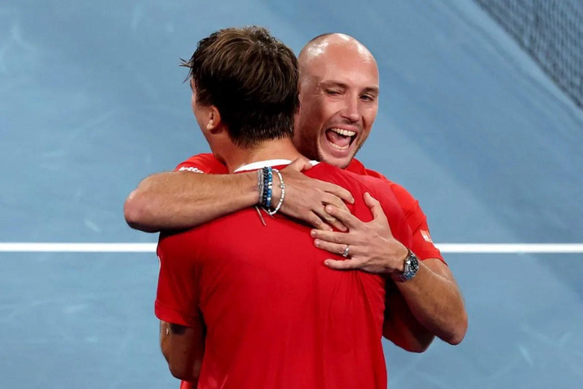 Belgium's Raphael Collignon (L) celebrates with team captain Steve Darcis after defeating Australia's Alek Vukic during the Davis Cup second-round qualifier tennis match at Ken Rosewall Arena in Sydney on September 14, 2025. DAVID GRAY / AFP