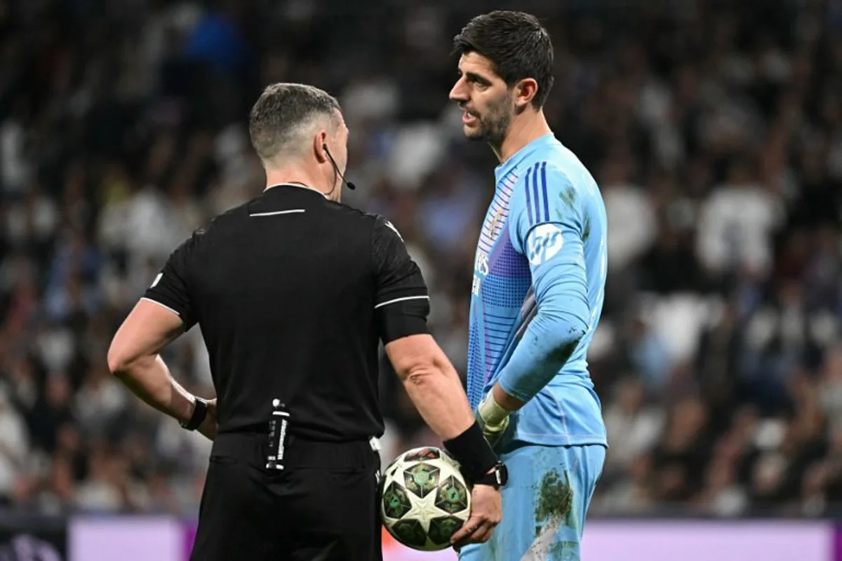 Romanian referee Istvan Kovacs speaks with Real Madrid's Belgian goalkeeper #01 Thibaut Courtois during the UEFA Champions League knockout phase play-off football match between Real Madrid CF and Manchester City at the Santiago Bernabeu stadium in Madrid on February 19, 2025.  JAVIER SORIANO / AFP