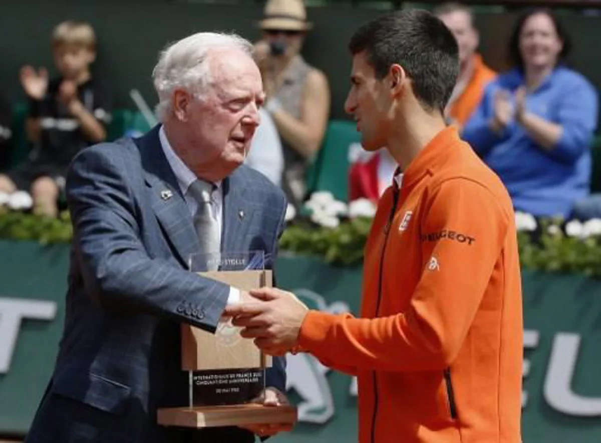 Former Australian player Fred Stolle, who won Roland Garros on May 30, 1965, shakes hands with Serbia's Novak Djokovic (R) after receiving an award at the Roland Garros 2015 French Tennis Open in Paris on May 30, 2015. AFP PHOTO / PATRICK KOVARIK