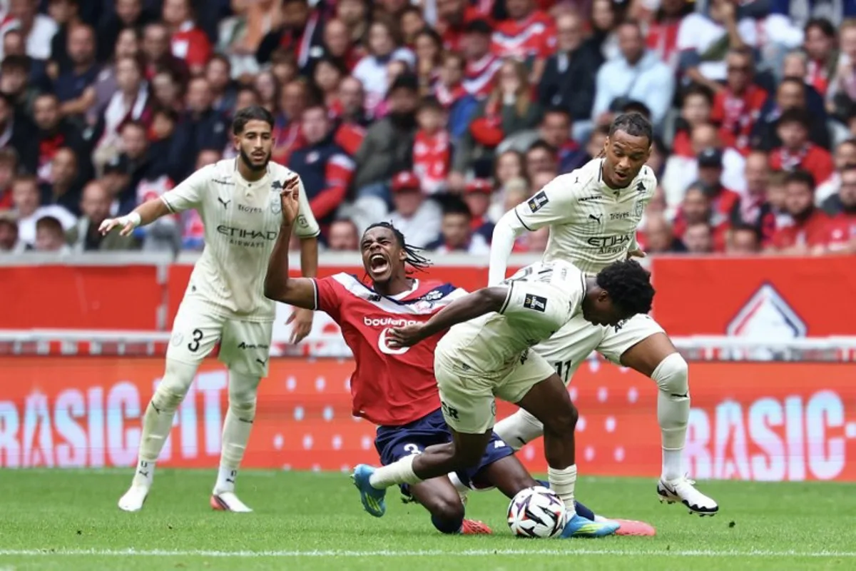 Lille's Belgian defender #03 Nathan Ngoy (2L) and Troyes' Togolese midfielder #29 Dermane Karim (2R) fight for the ball during the French L1 football match between Lille (LOSC) and Troyes (ESTAC) at the Stade Pierre-Mauroy in Villeneuve-d'Ascq on September 13, 2026.   Sameer AL-DOUMY / AFP