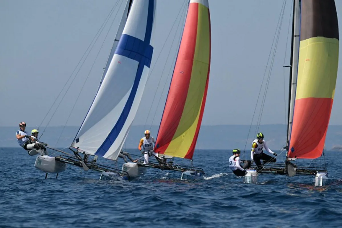 (LtoR) Finland's duo Sinem Kurtbay and Akseli Keskinen, Spain's duo Tara Pacheco van Rijnsoever and Andres Barrio Garcia and Belgium's duo Lucas Claeyssens and Eline Verstraelen compete in race 11 of the mixed Nacra 17 multihull event during the Paris 2024 Olympic Games sailing competition at the Roucas-Blanc Marina in Marseille on August 6, 2024.   NICOLAS TUCAT / AFP