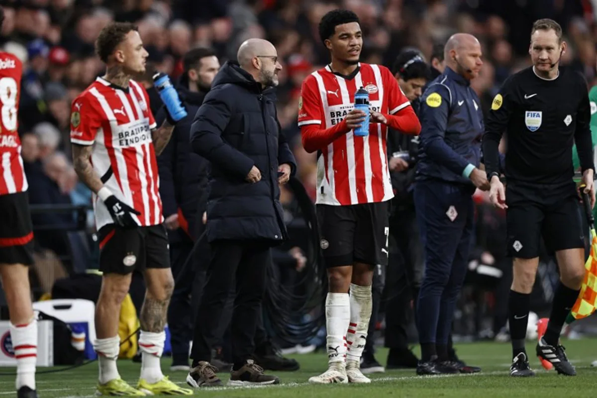 PSV's Dutch forward #07 Noa lang (L), PSV's Dutch head coach Peter Bosz (C) and PSV's US midfielder #10 Malik Tillman look on during the Dutch Eredivisie match between PSV Eindhoven and Feyenoord Rotterdam at Phillips Stadium in Eindhoven on December 22, 2024.  MAURICE VAN STEEN / ANP / AFP