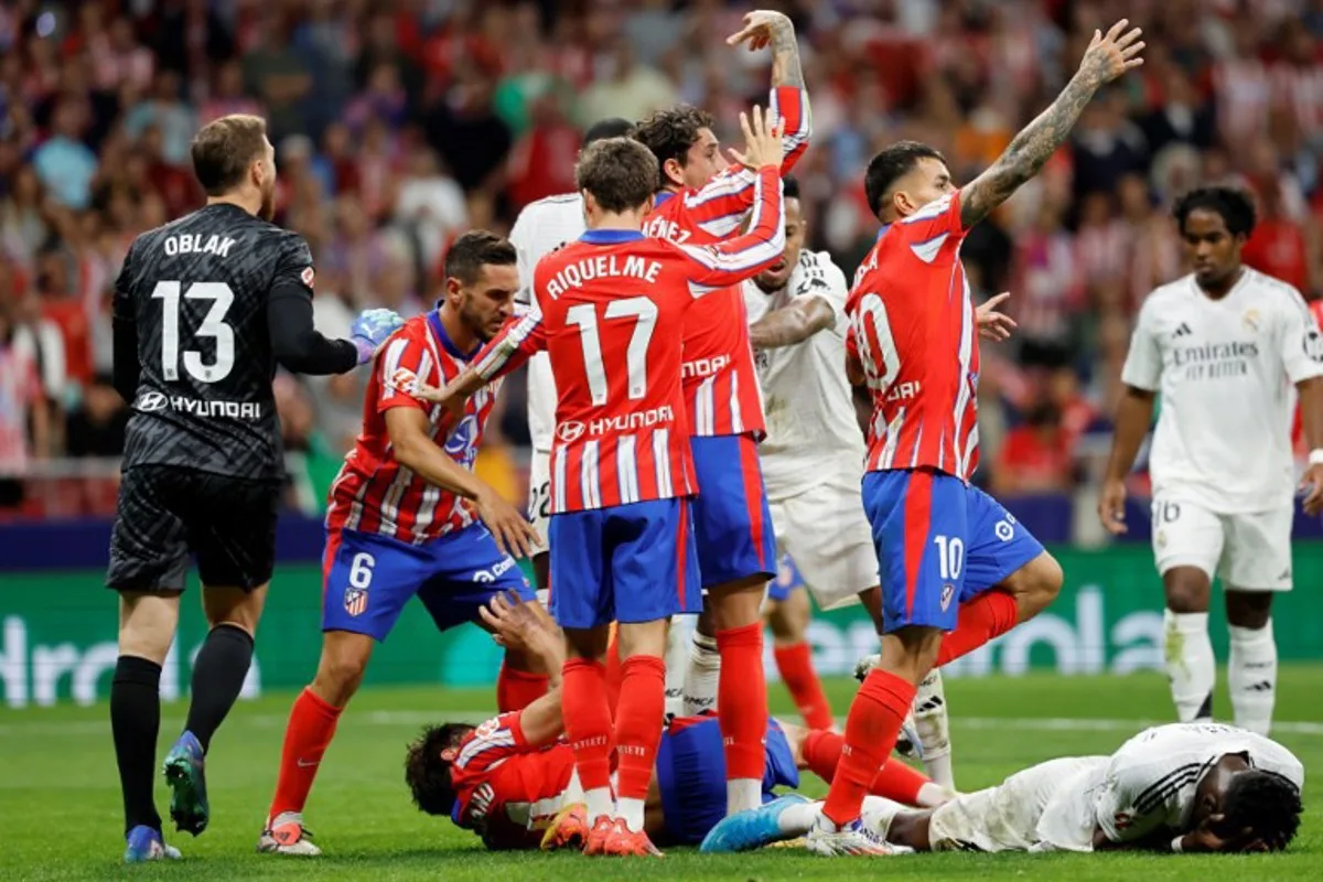 Real Madrid's French midfielder #14 Aurelien Tchouameni and Atletico Madrid's Spanish defender #24 Robin Le Normand lie on the ground during the Spanish league football match between Club Atletico de Madrid and Real Madrid CF at the Metropolitano stadium in Madrid on September 29, 2024.  OSCAR DEL POZO / AFP