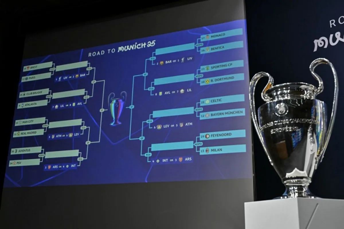 The trophy is on display next to a giant screen showing fixtures during the 2024-2025 UEFA Champions League football tournament knockout play-off draw at the House of European football in Nyon, on January 31, 2025.  Fabrice COFFRINI / AFP