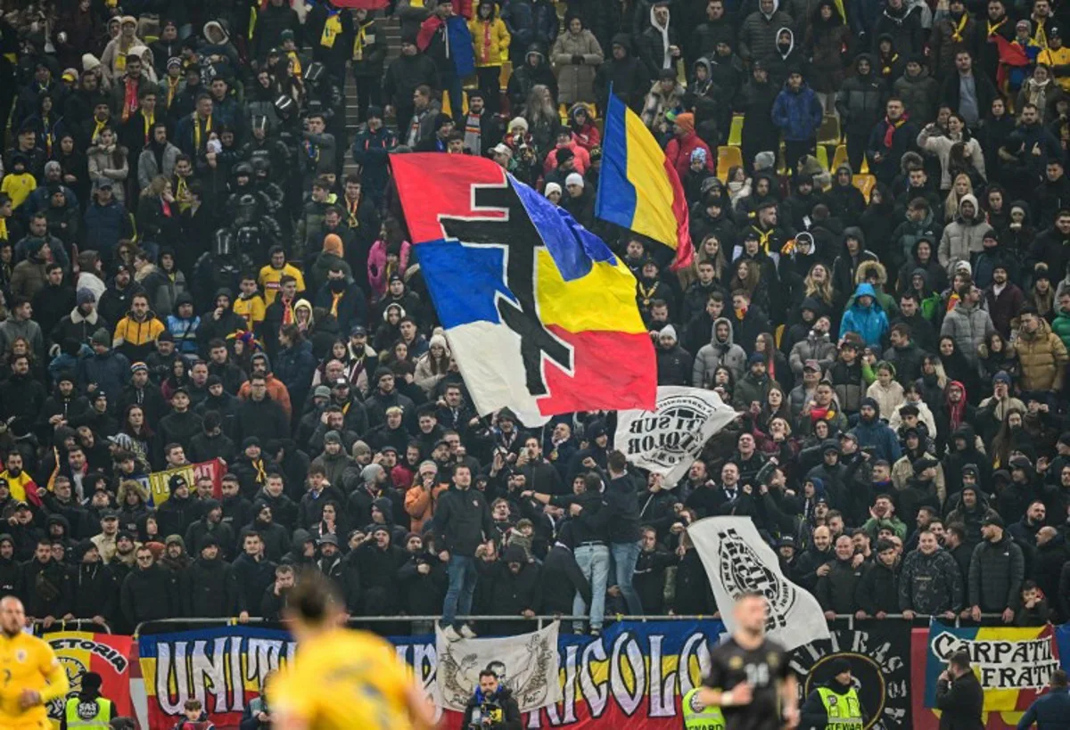 Romanian supporters wave a flag displaying Serbian and Romanian colors united by a Serbian Orthodox cross while chanting "Serbia, Serbia!"  before Kosovo's players left the pitch during the extra-time of the UEFA Nations League, League C, Group 2 football match between Romania and Kosovo in Bucharest, Romania on November 15, 2024.  Daniel MIHAILESCU / AFP