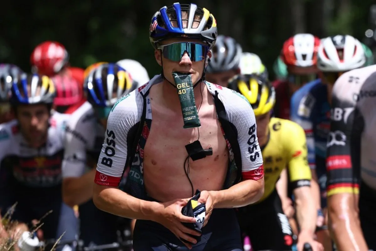 Red Bull - BORA - hansgrohe's Belgian rider Maxim Van Gils holds an energy gel in his mouth during the 7th stage of the 77th edition of the Criterium du Dauphine cycling race, 131,6 km between Grand-Aigueblanche and Valmeinier, on June 14, 2025. Anne-Christine POUJOULAT / AFP