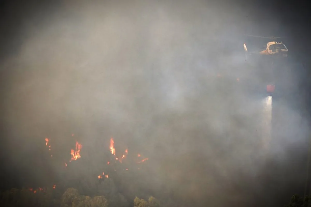 A firefighter helicopter drops water as a wildfire burns in Gondomar, northern Portugal on July 29, 2025. Almost 2,000 firefighters battled on July 29, 2025 to contain forest blazes across Portugal that have led to almost the whole country being put on high alert for fires. Ten major fires blazed with two in the north and three in the centre of the country causing most concern. CARLOS COSTA / AFP