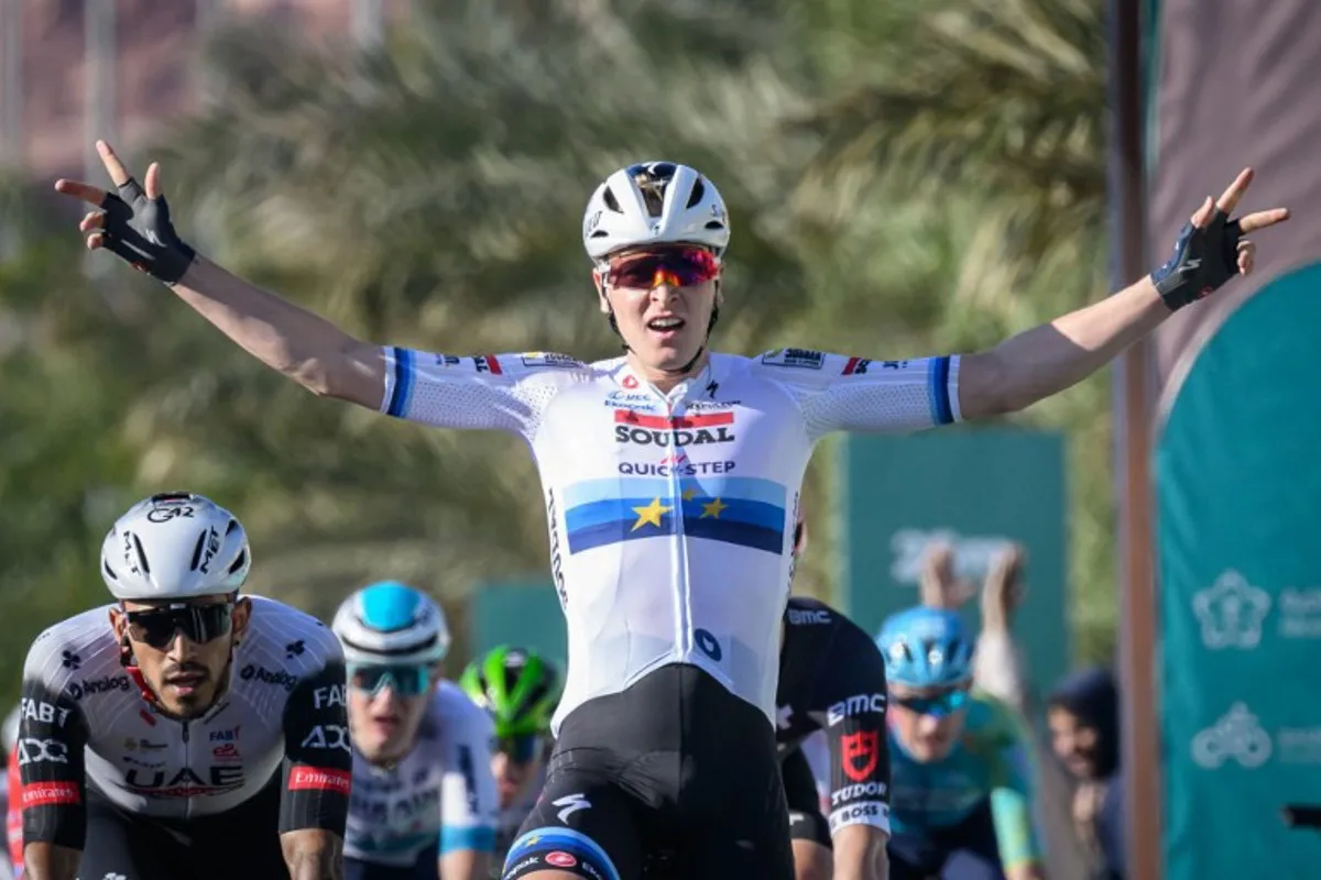 Team Soudal Quick-Step Belgian rider Tim Merlier celebrates as he crosses the finish line to win the first stage of the AlUla Tour cycling race from al-Manshiyah Train station to the al-Manshiyah Train Station, a 142.7 kilometers tour, in Alula, on January 28, 2025.  Loic VENANCE / AFP