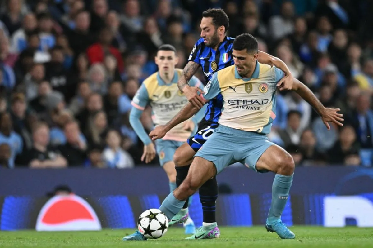 Inter Milan's Turkish midfielder #20 Hakan Calhanoglu (C) vies with Manchester City's Spanish midfielder #16 Rodri (R) during the UEFA Champions League, league phase football match between Manchester City and Inter Milan at the Etihad stadium, in Manchester, north-west England, on September 18, 2024  Oli SCARFF / AFP