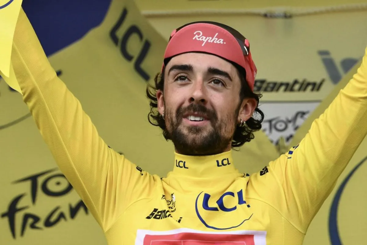 Guest and EF Education - EasyPost team's Irish rider Ben Healy celebrates on the podium with the overall leader's yellow jersey after the 10th stage of the 112th edition of the Tour de France cycling race, 165.3 km between Ennezat and Le Mont-Dore Puy de Sancy, in central France, on July 14, 2025. Marco BERTORELLO / AFP