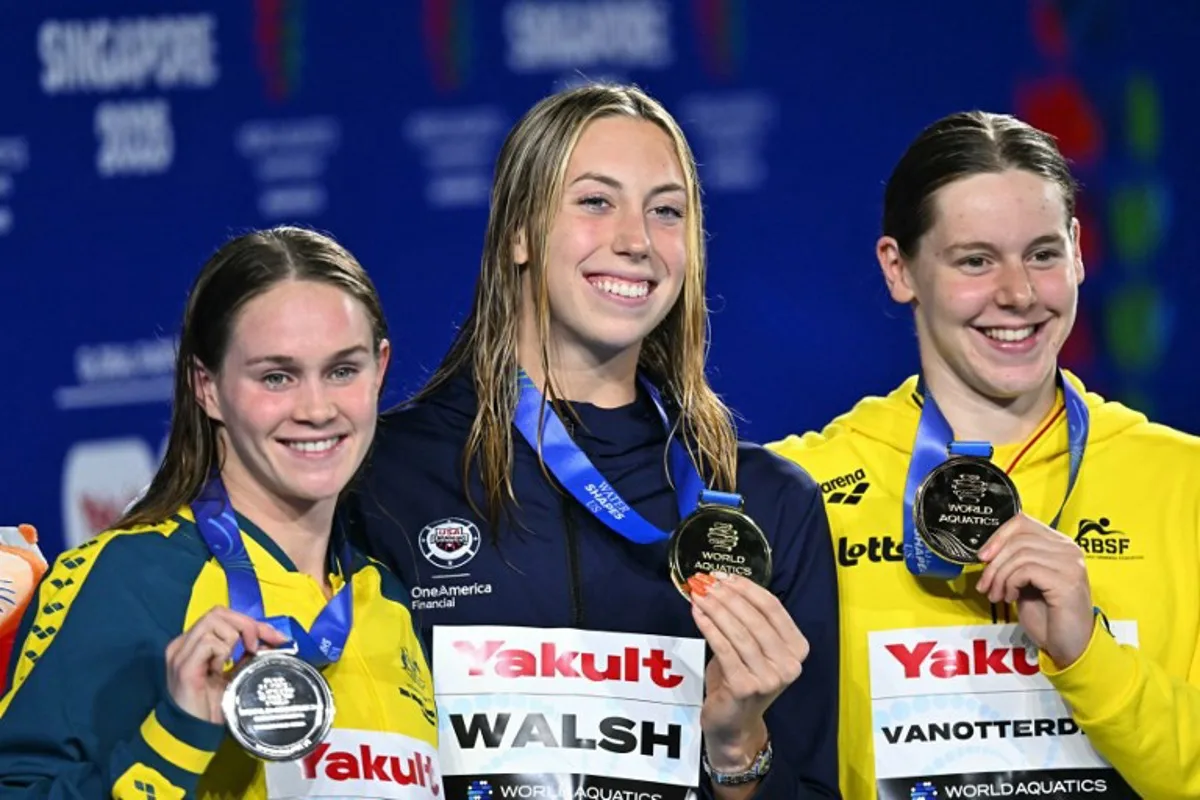 (L-R) Silver medallist Australia's swimmer Jamie Perkins, gold medallist US' swimmer Gretchen Walsh, and bronze medallist Belgium's swimmer Roos Vanotterdijk celebrate on the podium of the women's 50m butterfly swimming event during the 2025 World Aquatics Championships in Singapore on August 2, 2025. MANAN VATSYAYANA / AFP