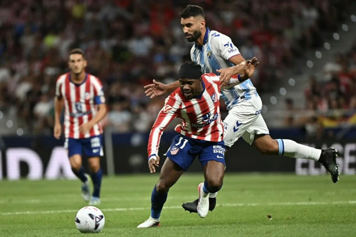 Atletico Madrid's Nigerian forward #11 Ademola Lookman vies with Malaga's Spanish defender #04 Einar Galilea (R) during the Spanish league football match between Club Atletico de Madrid and Malaga CF at the Metropolitano Stadium in Madrid on August 19, 2026. Javier SORIANO / AFP