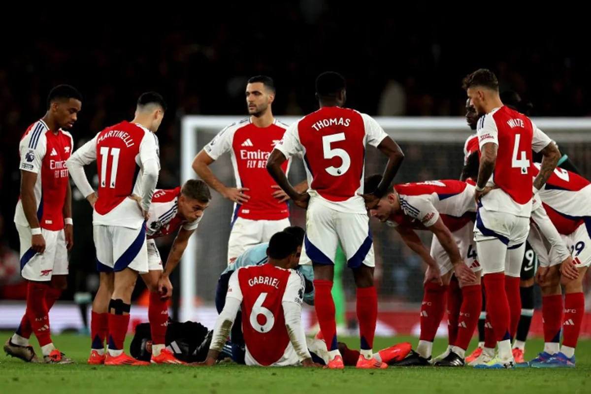 Arsenal players surround Arsenal's Brazilian defender #06 Gabriel Magalhaes as he sits on the floor injured during the English Premier League football match between Arsenal and Liverpool at the Emirates Stadium in London on October 27, 2024.   Adrian Dennis / AFP