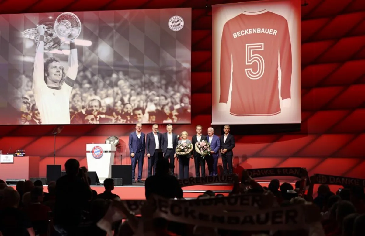 (Bottom L-R)  First vice president of FC Bayern Munich eV Dieter Mayer, CEO of FC Bayern Munich AG Jan-Christian Dreesen, President of the German Bundesliga football club Bayern Munich eV and Member of the Supervisory Board of FC Bayern Munich AG Herbert Hainer, Franz Beckenbauer's widow Heidi, Franz Beckenbauer's son Joel Beckenbauer, Deputy vice president of FC Bayern Munich eV Walter Mennekes, and Deputy CEO of FC Bayern Munich AG Michael Diederich react on stage during the annual general meeting of the FC Bayern Munich eV in Munich on December 8, 2024, after the announcement that in honor of former Bayern Munich's football legend Franz Beckenbauer, the number 5 jersey (On display) will be retired and will forever belong to Beckenbauer. With around 382,000 members, FC Bayern Munich eV is the world's largest sports club. Founded in 1900, the club is best known for its soccer department, which was partially spun off into FC Bayern Munich AG in 2001. This year's annual general meeting will also honor Franz Beckenbauer, known as "the Kaiser," who passed away in January 2024. Alexandra BEIER / AFP