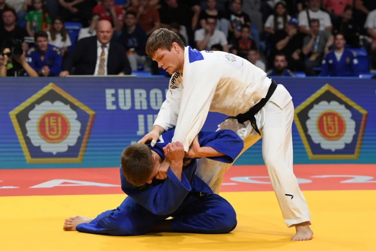 Germany's Fabian Kansy (Blue) and Belgium's Matthias Casse (White) compete in the men's -90 kg bout during the Judo's European Championships in Podgorica, on April 27, 2025. The tournament is taking place from April 23 to 27, 2025. SAVO PRELEVIC / AFP