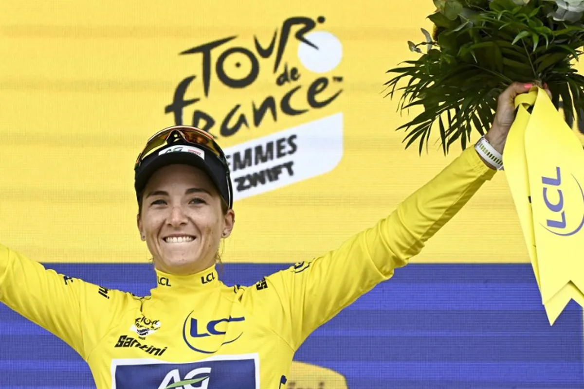 AG Insurance - Soudal Team's Mauritius rider Kimberley Le Court Pienaar celebrates on the podium with the overall leader's yellow jersey after the 2nd stage (out of 9) of the fourth edition of the Women's Tour de France cycling race, 110,4 km from Brest to Quimper on July 27, 2025. JULIEN DE ROSA / AFP