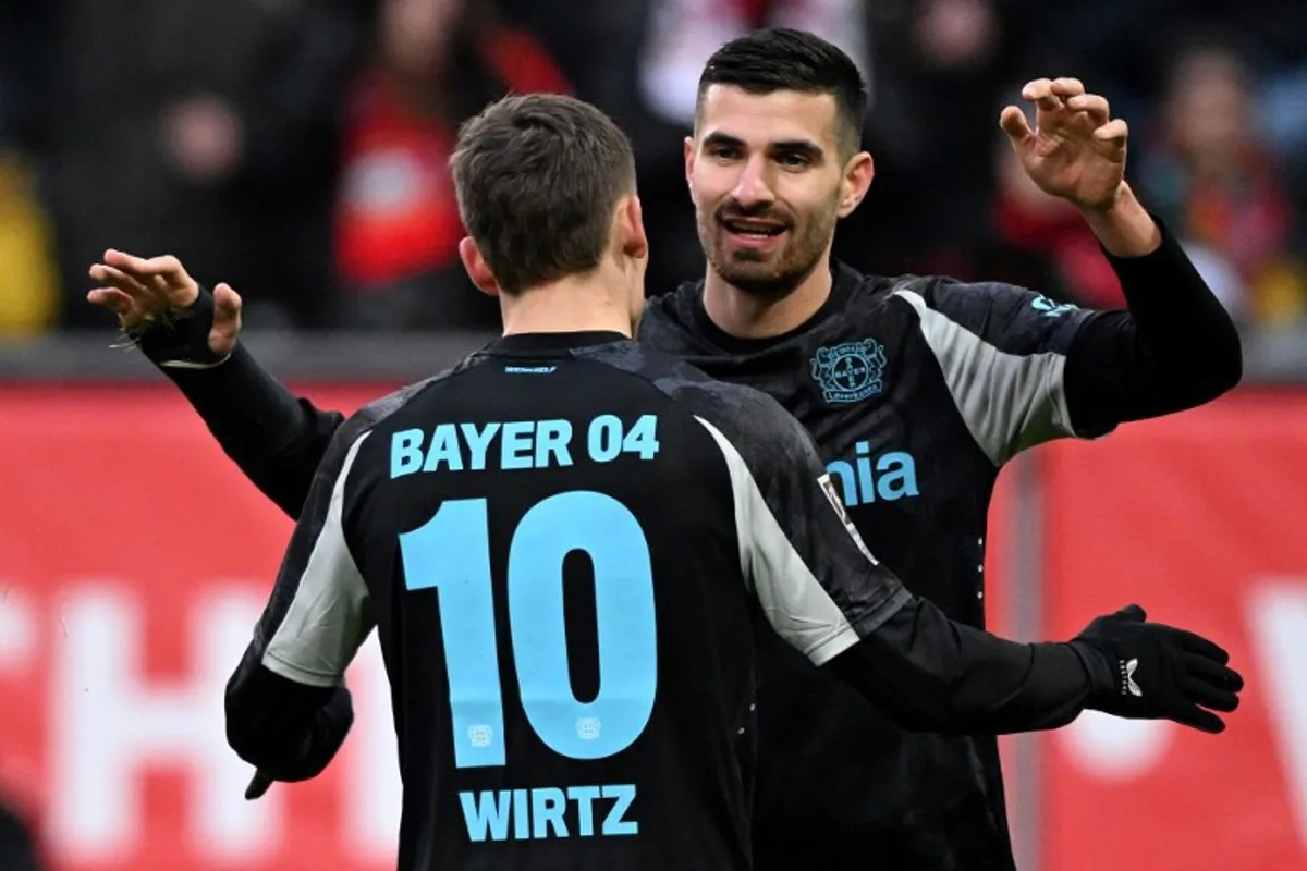 Bayer Leverkusen's French forward #11 Martin Terrier (R) celebrates scoring a goal during the German first division Bundesliga football match between FC Augsburg and Bayer 04 Leverkusen in Augsburg on December 14, 2024.  Kirill KUDRYAVTSEV / AFP