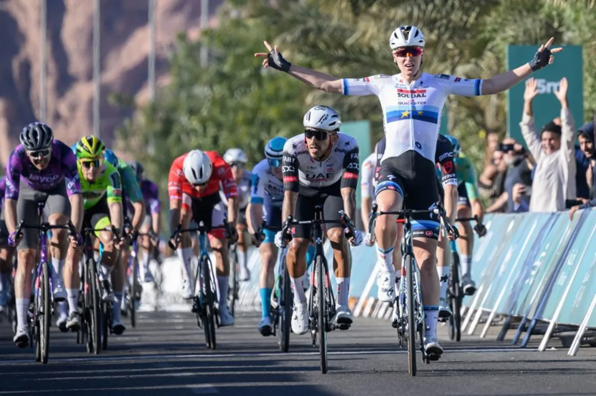 Team Soudal Quick-Step Belgian rider Tim Merlier celebrates as he crosses the finish line to win the first stage of the AlUla Tour cycling race from al-Manshiyah Train station to the al-Manshiyah Train Station, a 142.7 kilometers tour, in Alula, on January 28, 2025.  Loic VENANCE / AFP