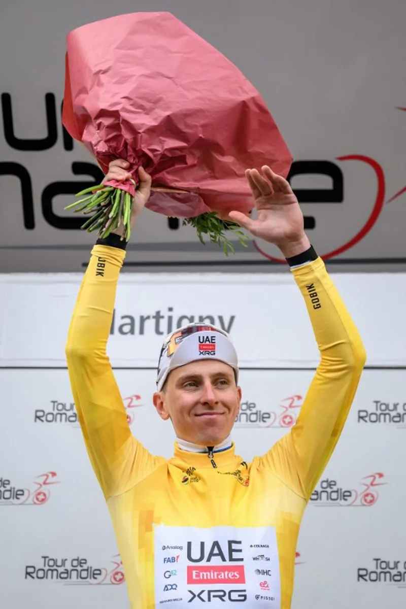 UAE Team Emirates-XRG's Slovenian rider Tadej Pogacar wearing the overall leader's yellow jersey celebrates on the podium of the first stage of the Tour of Romandie UCI cycling World tour, a 171.2 km loop from Martigny-Ville to Martigny-Ville, in Martigny, on April 29, 2026.  Fabrice COFFRINI / AFP