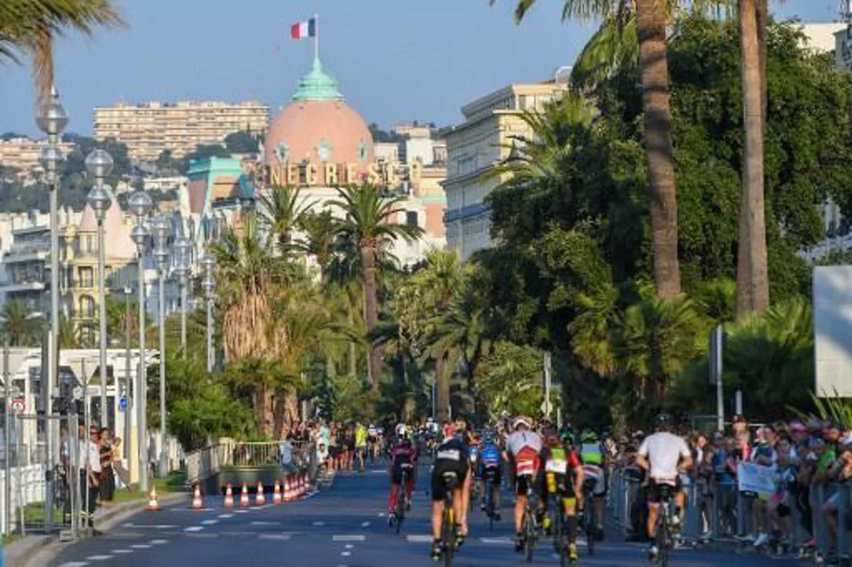 Competitors take the start of the bicycle race after completing the swimming race of the 13th Ironman thriathlon in Nice on July 23, 2017, with the Negresco Hotel in background.  YANN COATSALIOU / AFP