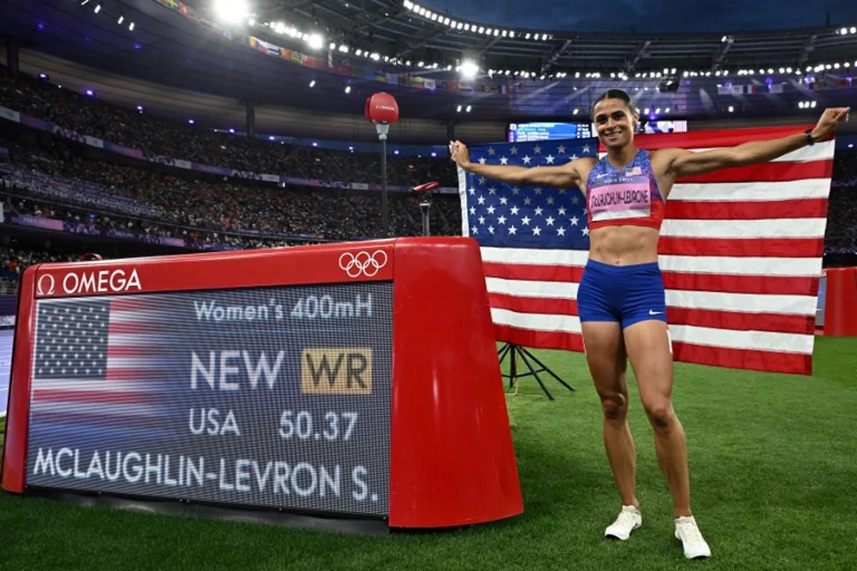 Gold medallist US' Sydney Mclaughlin-Levrone celebrates by the score board after winning the women's 400m hurdles final of the athletics event and after breaking a new world record during the Paris 2024 Olympic Games at Stade de France in Saint-Denis, north of Paris, on August 8, 2024.  Ben STANSALL / AFP