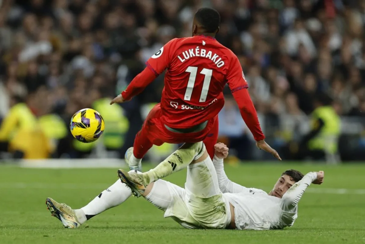 Sevilla's Belgian forward #11 Dodi Lukebakio and Real Madrid's Uruguayan midfielder #08 Federico Valverde vie for the ball during the Spanish league football match between Real Madrid CF and Sevilla FC at the Santiago Bernabeu stadium in Madrid on December 22, 2024.  OSCAR DEL POZO / AFP