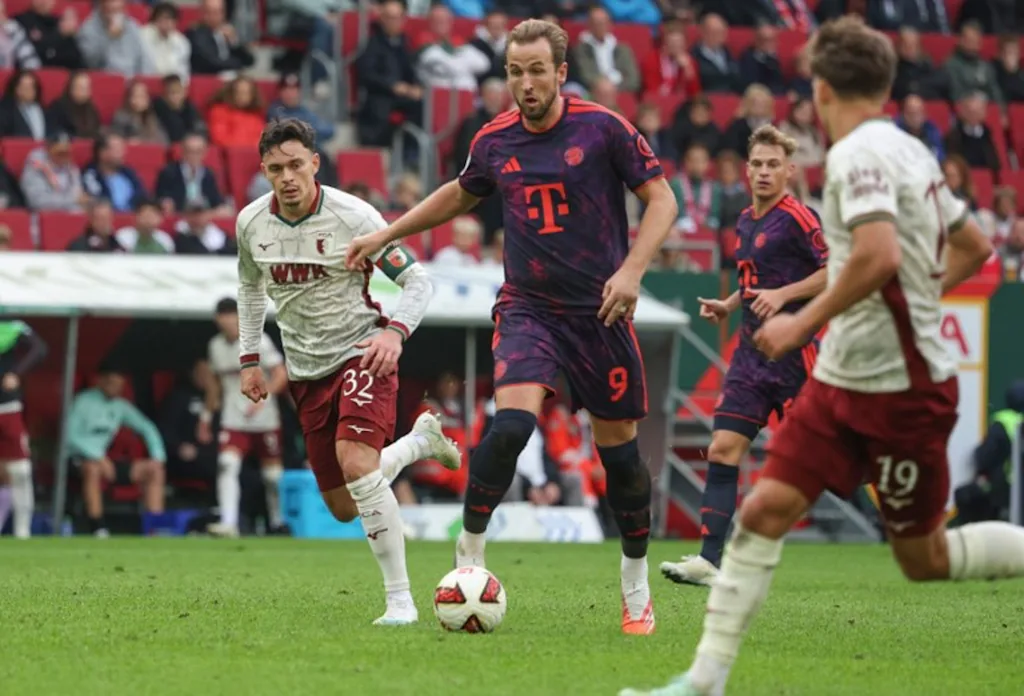 Bayern Munich's English forward #09 Harry Kane (C) and Augsburg's Swiss midfielder #32 Fabian Rieder (L) vie for the ball during the German first division Bundesliga football match between FC Augsburg and FC Bayern Munich in Augsburg, southern Germany on October 10, 2026.  Karl-Josef HILDENBRAND / AFP