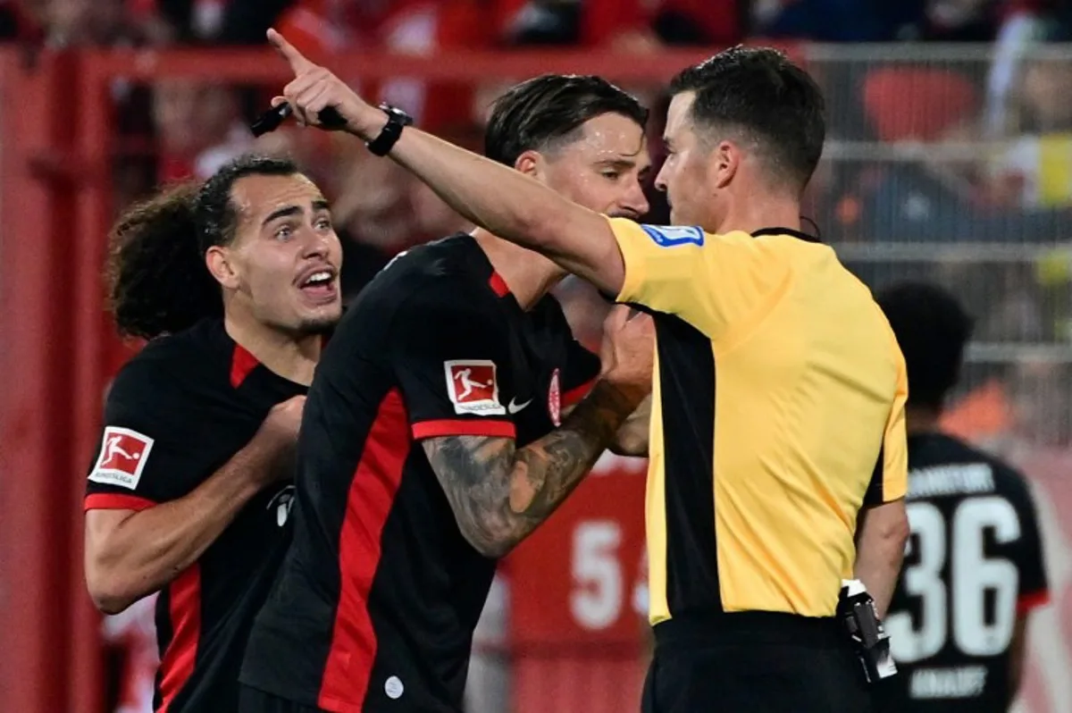 Frankfurt's German defender #04 Robin Koch (C) pleads with German referee Harm Osmers after he sent Frankfurt's Belgian defender #03 Arthur Theate (L) off during the German first division Bundesliga football match between Union Berlin and Eintracht Frankfurt in Berlin on October 27, 2024.  John MACDOUGALL / AFP