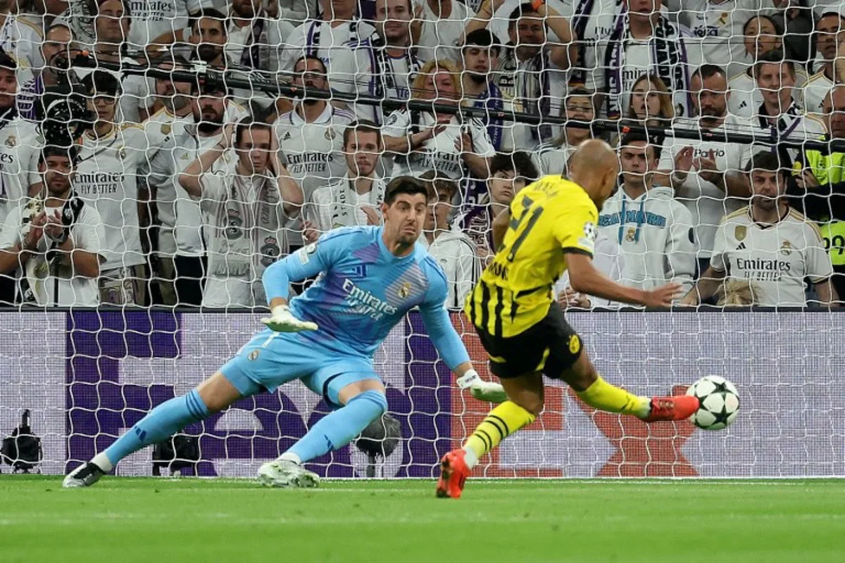 Borussia Dortmund's Dutch forward #21 Donyell Malen scores a goal past Real Madrid's Belgian goalkeeper #01 Thibaut Courtois during the UEFA Champions League, league phase day 3 football match between Real Madrid CF and Borussia Dortmund at the Santiago Bernabeu stadium in Madrid on October 22, 2024.  Pierre-Philippe MARCOU / AFP