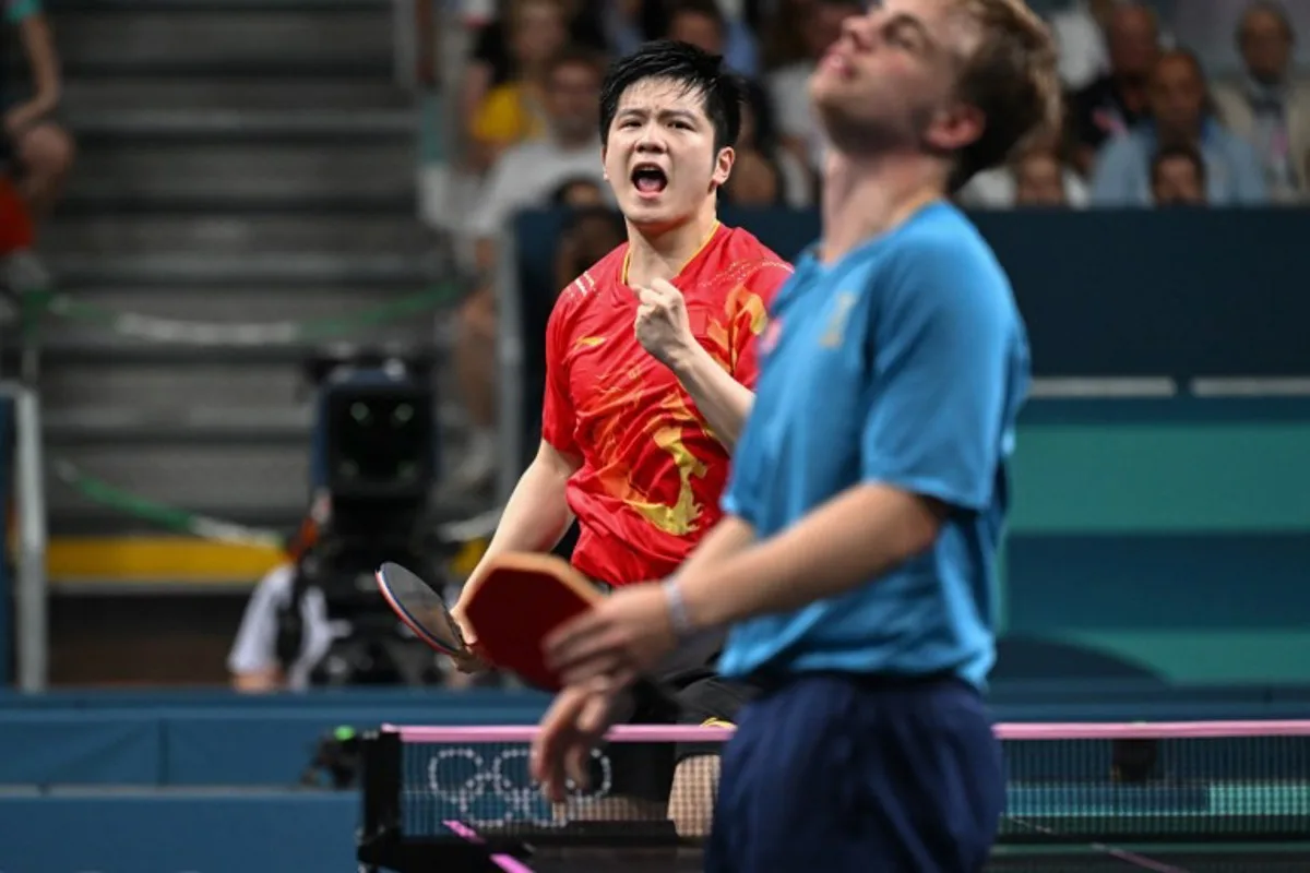 China's Fan Zhendong (L) celebrates a point as Sweden's Truls Moregard (R) reacts during his men's table tennis singles match in the team gold medal match between China and Sweden at the Paris 2024 Olympic Games at the South Paris Arena in Paris on August 9, 2024.  JUNG Yeon-je / AFP